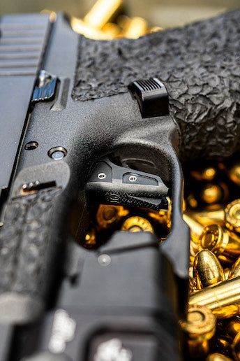 JG Vex trigger in Glock on top of shiny gold bullets